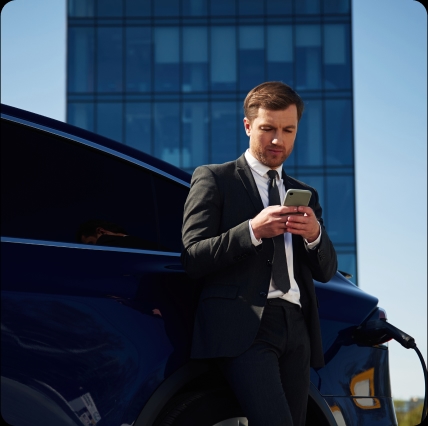 Mann vor Auto mit Handy in der Hand